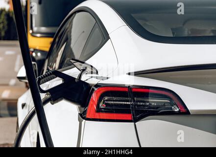 Vue arrière du chargement de la voiture en tesla blanche à la station de charge EV Banque D'Images