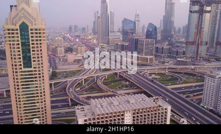 Vue sur les gratte-ciels modernes et les autoroutes animées le soir dans le centre-ville de luxe de Dubaï.Vue aérienne supérieure depuis le toit de la tour.Circulation aux intersections. Banque D'Images