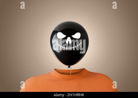 Un homme avec un ballon noir d'Halloween au lieu de la tête.Concept Halloween minimal. Banque D'Images