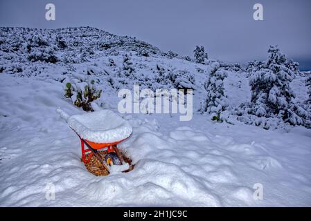 Une ancienne barrow de roue assise sur la pente de Sullivan Butte dans la vallée de Chino AZ recouverte de neige d'une tempête hivernale de nuit. Banque D'Images