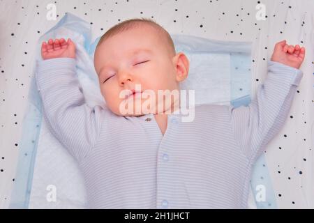 Le bébé dort dans une posture en forme d'étoile avec ses bras écartées sur un lit d'enfant.Enfant de trois mois Banque D'Images