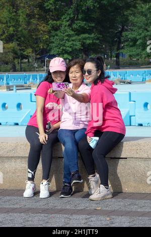 Deux femmes sourdes et un guide prennent des selfies près de Unisphere dans le parc Corona de Flushing Meadows à Queens, New York. Banque D'Images