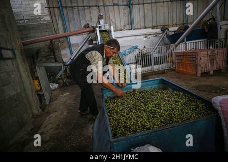 Gaza.18 octobre 2021.Un palestinien travaille dans un moulin à olives traditionnel au camp de réfugiés de Nuseirat, dans le centre de la bande de Gaza, le 18 octobre 2021.La saison de récolte de l'olive a commencé dans les territoires palestiniens depuis le début du mois d'octobre et dure environ 40 jours, de nombreux Palestiniens faisant de l'huile d'olive et du savon pour eux-mêmes ainsi que pour la vente.Credit: Rizek Abdeljawad/Xinhua/Alamy Live News Banque D'Images