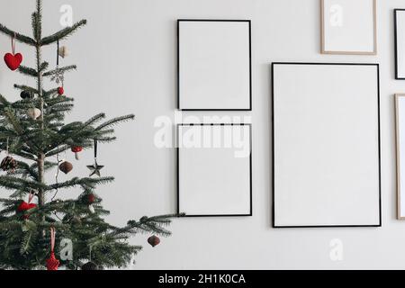 Intérieur de Noël.Sapin décoré avec ornements d'hiver traditionnels suspendus.Ensemble de maquettes noir et en bois pour cadres de portrait.Art mural Banque D'Images