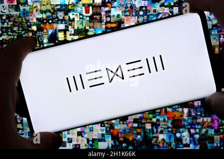Le logo de la plate-forme Beeple WENEW de l'artiste numérique est visible sur son smartphone et son collage d'art numérique NFT « Everydays the First 5000 Days » sur fond flou. Banque D'Images