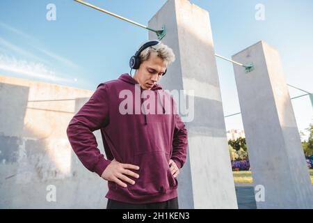 Sportsman se réchauffe, fait des exercices de rotation du cou et écoute de la musique dans les écouteurs.Photo de style de vie urbain Banque D'Images