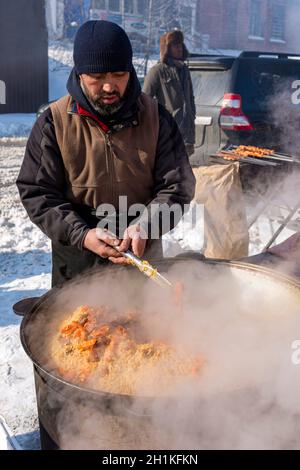 Pilaf chaud dans une cuve en fer.Viande de riz et carottes.De la vapeur s'échappe.Pilaf interfère avec une cuillère. Banque D'Images