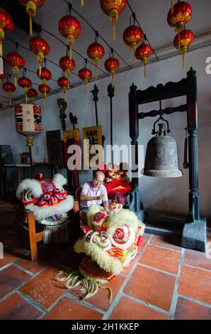 Georgetown, Penang/Malaysia - Jul 08 2016: Un vieil homme nettoie la tête de danse traditionnelle chinoise du lion dans le temple. Banque D'Images