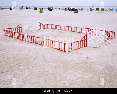 Paysage de plage allemand de la mer du Nord avec un petit terrain de jeu de boules de plage clôturé en premier plan et des chaises de plage en osier numérotées loin derrière avec un Banque D'Images