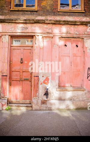 Londres, Royaume-Uni - 4 janvier 2019: Portrait vue d'une petite fille peint sur un mur entre la porte et la fenêtre d'un bâtiment rouge détérioré de Lon Banque D'Images