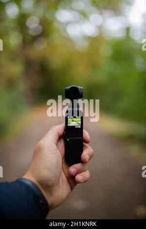 Londres, Royaume-Uni - 4 janvier 2019: Portrait vue d'une main tenant un DJI Osmo Pocket Camera Gimbel enregistrement de la forêt floue en arrière-plan Banque D'Images