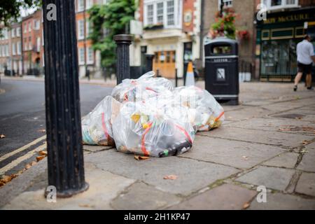 Photo de sacs en plastique de déchets abandonnés sur le trottoir à côté d'un lampadaire dans une rue de Londres, Royaume-Uni Banque D'Images