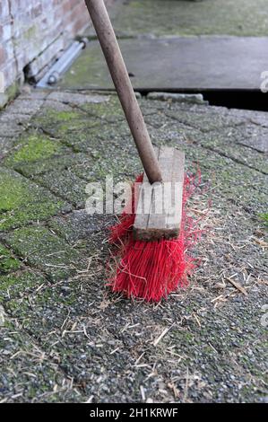 Gros plan d'un balai à poils rouges, utilisé pour nettoyer une chaussée en béton Banque D'Images