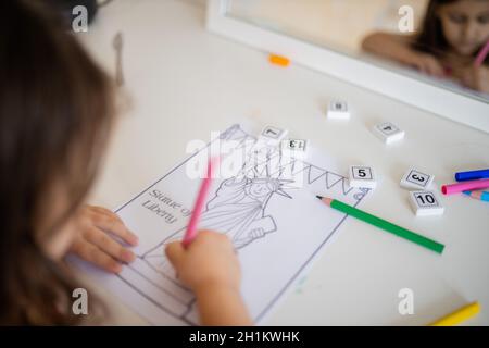 Sur l'épaule d'une petite fille brune devant un miroir qui colore une image de la Statue de la liberté Banque D'Images