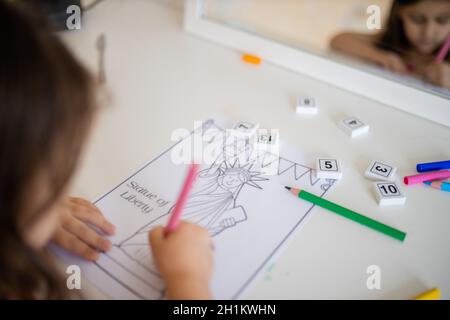 Sur l'épaule d'une petite fille brune devant un miroir qui colore une image de la Statue de la liberté Banque D'Images