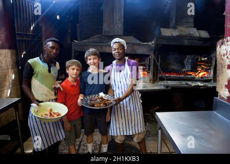 Tween garçons cuisant avec des Sud-Africains locaux à Mzoli's dans la commune de Gugulethu Banque D'Images