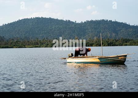 Pahang, Malaisie: 16 octobre 2021 - Un pêcheur pêchant sur un bateau sur le lac Chini à l'aide d'un filet.Points de mise au point sélective Banque D'Images