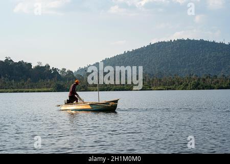 Pahang, Malaisie: 16 octobre 2021 - Un pêcheur pêchant sur un bateau sur le lac Chini à l'aide d'un filet.Points de mise au point sélective Banque D'Images