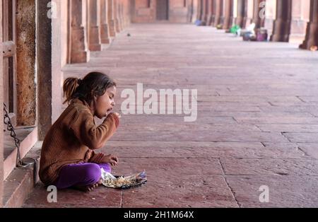 Une pauvre fille mangeant dans le complexe Fatehpur Sikri, Uttar Pradesh, Inde Banque D'Images