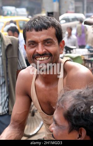 Un pilote indien de pousse-pousse pose assis sur un pousse-pousse tricycle à Kolkata, en Inde Banque D'Images