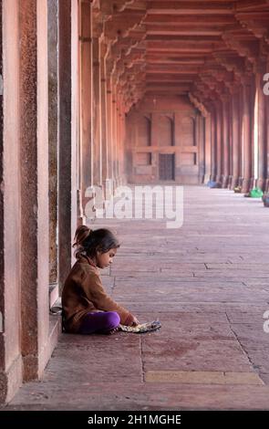 Une pauvre fille mangeant dans le complexe Fatehpur Sikri, Uttar Pradesh, Inde Banque D'Images