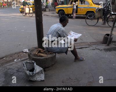 Rues de Kolkata, homme lisant le journal tout en ignorant tout autour de lui. Banque D'Images