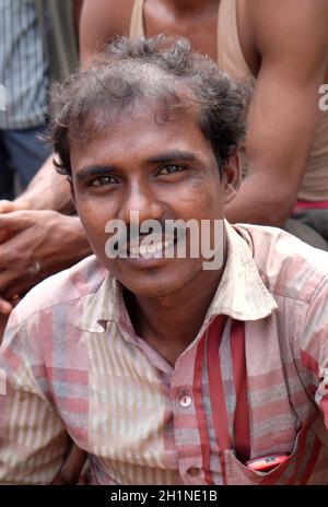 Un pilote indien de pousse-pousse pose assis sur un pousse-pousse tricycle à Kolkata, en Inde Banque D'Images