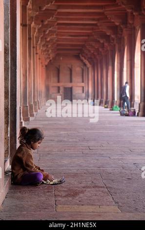 Une pauvre fille mangeant dans le complexe Fatehpur Sikri, Uttar Pradesh, Inde Banque D'Images