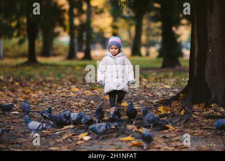 jeune fille blonde pourchassant les oiseaux dans le parc, automne Banque D'Images