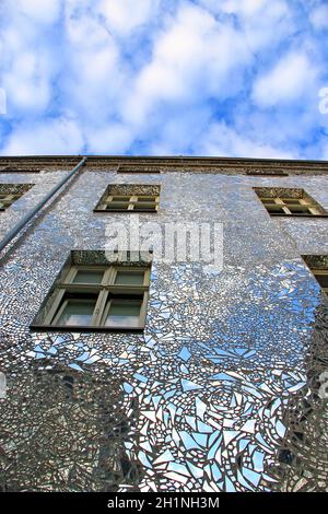 Bâtiment avec murs symétrisés. Façade de bâtiment en fragments de miroir. Murs de maison couverts de pièces de miroir. Fenêtres du bâtiment avec wal Banque D'Images