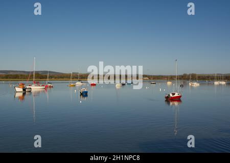 Bateaux amarrés à Dell Quay dans Chichester Harbour, West Sussex, Angleterre. Avec un ciel bleu clair et une eau calme et plate. Banque D'Images