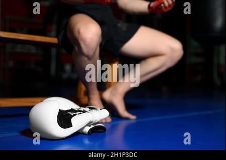 Gros plan des jambes du boxeur reposant sur un banc en salle de gym après l'entraînement. Photo de haute qualité Banque D'Images