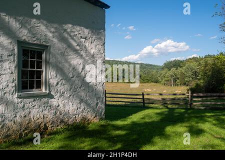 Scène pastorale idyllique avec pâturage des moutons et l'extérieur d'un cottage en pierre coloniale américain blanchi à la chaux. Banque D'Images