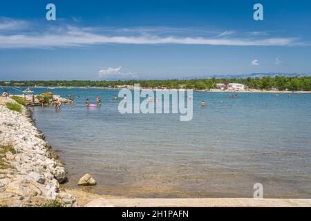 Zaton, Croatie, juillet 2019 familles s'amuser dans les eaux turquoise de la mer Adriatique avec jetée rocheuse avec Alpes Dinaric en arrière-plan Banque D'Images