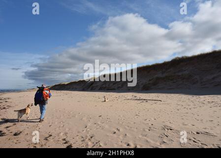 Un homme et son chien marchent le long d'une plage déserte à l'Île-du-Prince-Édouard, dans les provinces Maritimes, au Canada, à Greenwich, dans le parc national de l'Île-du-Prince-Édouard. Banque D'Images