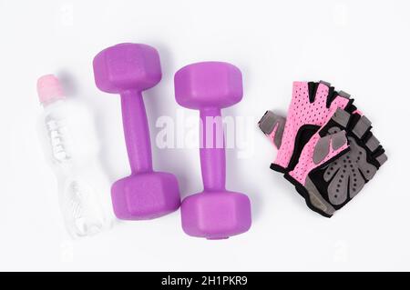 gants de sport roses, paire d'haltères violettes et bouteille d'eau sur fond blanc, style de vie sain Banque D'Images