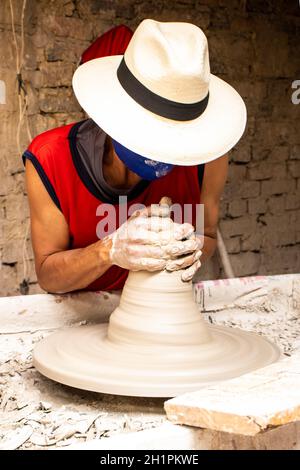 Homme faisant des articles en céramique sur la roue de potiers dans un Usine traditionnelle dans la ville de Ráquira située dans le département de Cundinamarca en Colombie Banque D'Images