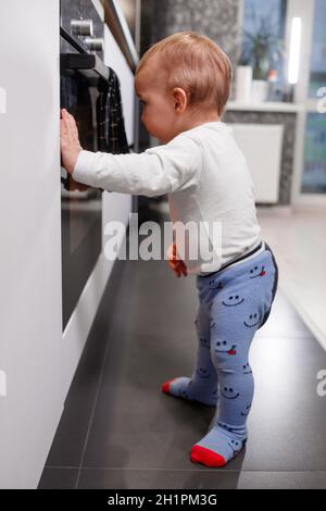 Petit enfant jouant avec cuisinière électrique dans la cuisine Banque D'Images