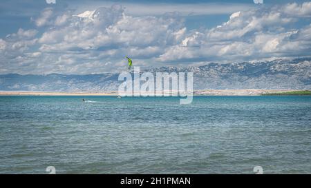 Vue depuis la plage de Zdrijac entre la baie de Nin et la mer Adriatique sur les kitesurf ou kitesurf avec la chaîne de montagnes des Alpes Dinaric en arrière-plan, Croatie Banque D'Images