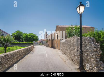 Rue avec des bâtiments anciens et vintage, lampe de rue éclairée, murs en pierre et église en arrière-plan. Vieux quartier de la ville de Nin situé sur la petite île, Croatie Banque D'Images