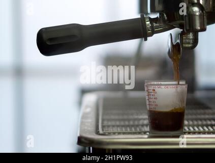 Machine espresso verser le café dans une tasse graduée. Gros plan Banque D'Images