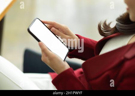 Gros plan femme d'affaires en costume rouge décontracté tenant un smartphone moderne avec une maquette d'écran blanche. Banque D'Images