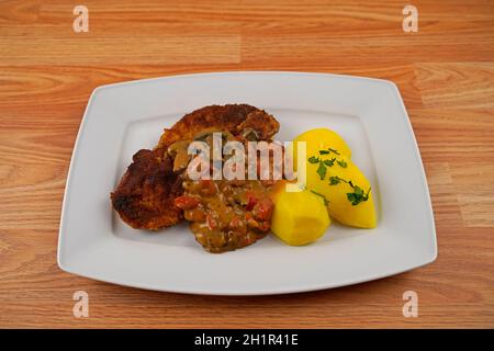 porc pané aux pommes de terre et aux champignons, sauce paprika sur une assiette de service blanche Banque D'Images