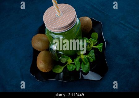 Smoothie aux feuilles de saladet au kiwi sur une assiette noire et décorée avec kiwi et laitue Banque D'Images