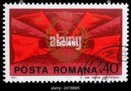 Timbres en Roumanie montre les drapeaux rouges et du parti communiste d'un insigne, 50 ans P.C.R., vers 1971. Banque D'Images