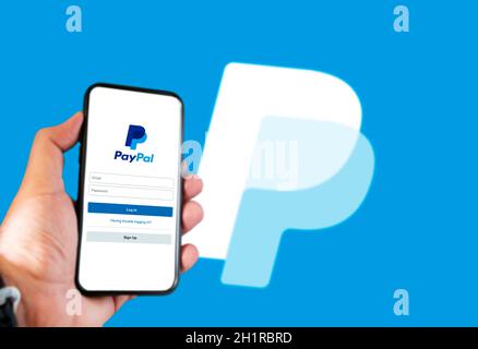 Rome, Italie, le 16 février 2021: Main tenant un smartphone avec page de connexion de l'application Paypal à l'écran et logo Paypal flou en arrière-plan. Transfert d'argent Banque D'Images