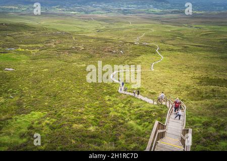 Enniskillen, Irlande du Nord, août 2019 personnes randonnée sur une promenade en bois, escalade sur des marches abruptes et des escaliers pour atteindre le sommet de la montagne Cuilcagh Banque D'Images