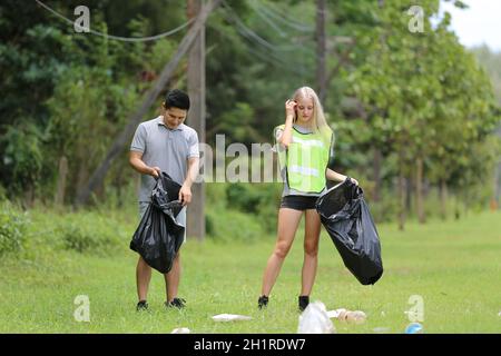 les jeunes bénévoles collectent des bouteilles en plastique dans des sacs à ordures en milieu forestier. Banque D'Images