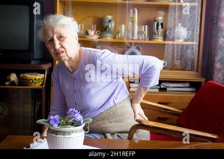 Femme âgée de 75s avec des sentiments douloureux massant bas de dos pour réduire la douleur, mal de dos inconfort.Maladies des personnes âgées, lésion du nerf sciatique Banque D'Images