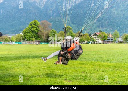 Interlaken, Switzerland - May 26, 2016: Tandem paragliding landing after flight over the Swiss Alps in Interlaken, Switzerland. Stock Photo